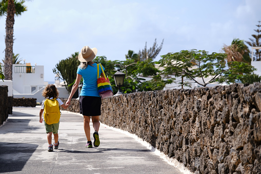 Mother with lgtbi flag bag holds hands with her toddler son