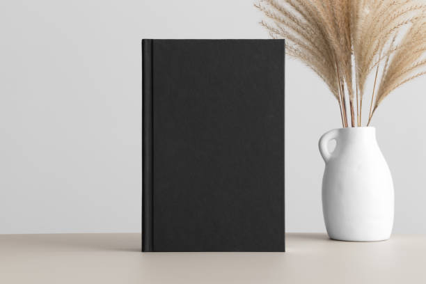 istock Black book mockup with a reed pampas decoration on the beige table. 1480969290