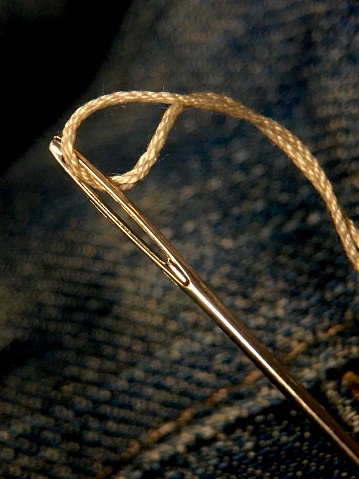 Spool of thread with needle isolated on white, studio shot.
