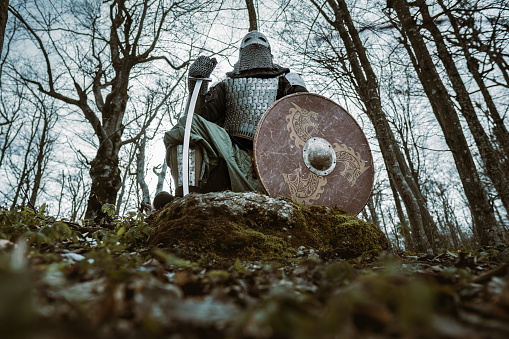 Portrait of unrecognizable medieval warrior with a helmet, sword and shield