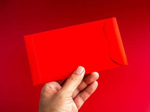 istock A red envelope, vertical style, holding by hand isolated on red background. Hongbao packet for lucky money gift in Chinese lunar, new year on January month, wedding red packet. 1480974790