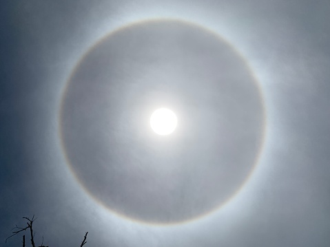 A halo is an optical phenomenon produced by light interacting with ice crystals suspended in the atmosphere. Halos can have many forms, ranging from colored or white rings to arcs and spots in the sky. Many of these appear near the Sun or Moon, but others occur elsewhere or even in the opposite part of the sky.