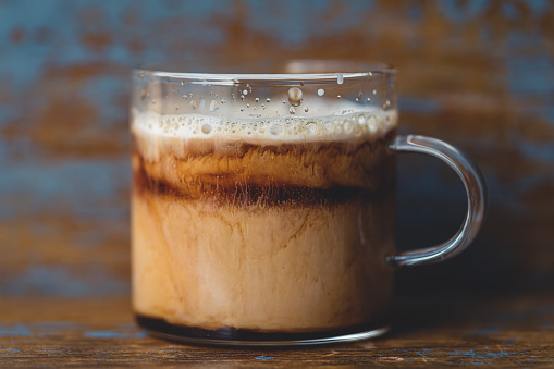 Milk dripping into coffee in glass