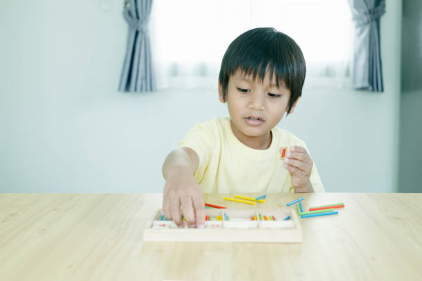 istock Asian kindergarten boy learning math by playing and counting wooden sticks toy. 1480977658
