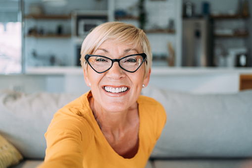 Shot of beautiful mature woman having video call at home. Shot of a senior woman using smartphone for video conference.