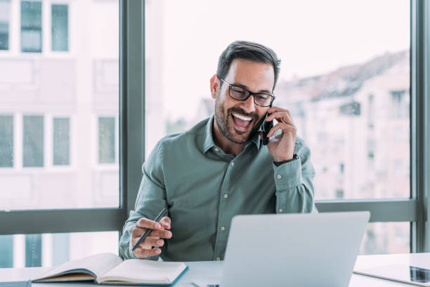 istock Businessman working on laptop and talking on cellphone. 1480979219