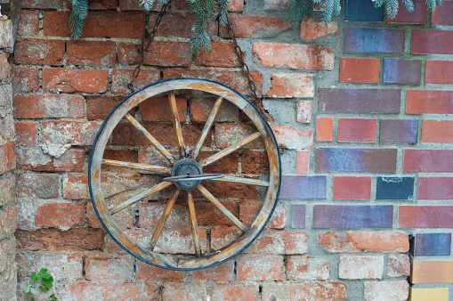 old stone brick wall with an old wooden wheel hanging on wall old village