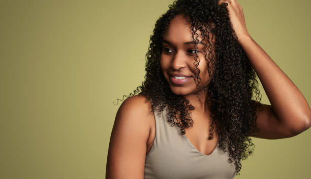 istock Smiling black woman touching curly hair in studio 1480981810