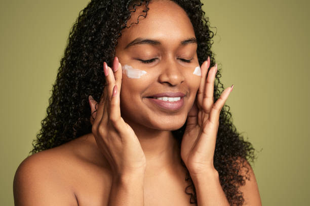 istock Smiling black woman applying cream on face 1480981856