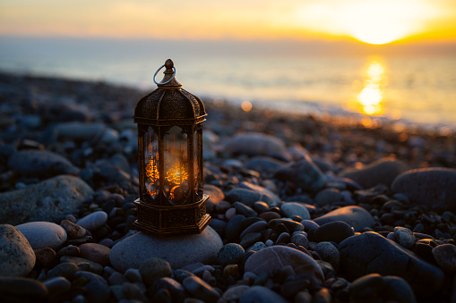 Ramadan Mubarak, Muslim lantern glows on the seashore at sunset,copy space