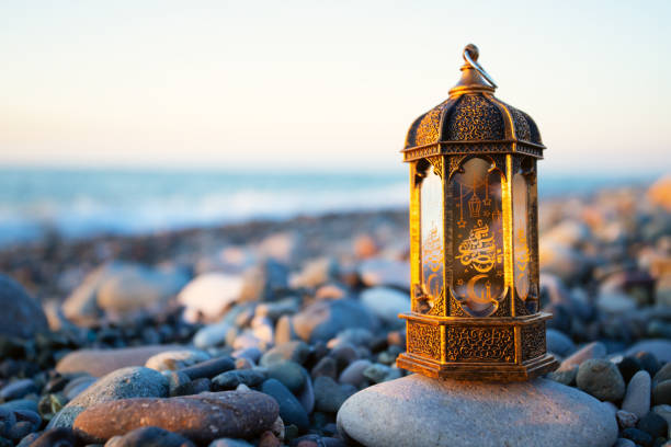 istock ramadan kareem iftar, muslim lantern lamp glows on the seashore at sunset,copy space 1480982447