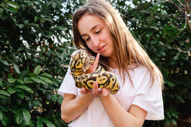Young woman holding her pet snake outdoors.