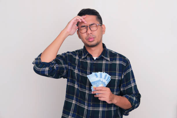 homme asiatique adulte montrant un geste de stress tout en tenant de l’argent - pusing photos et images de collection