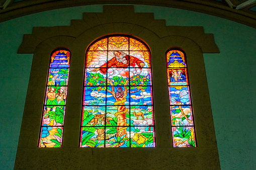 Colorful stained glass filters sunlight as it falls upon the chapel window sill.