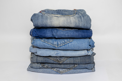 A pile of well-cleaned used jeans on a white background.