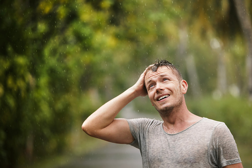 Portrait of man in wet clothes enjoying heavy rain in nature. Themes of life water, weather and environment.