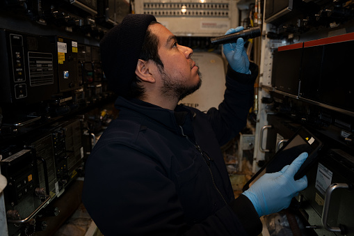 Aircraft Technician inspecting and working in the main electronics bay of a 757 commercial airplane.