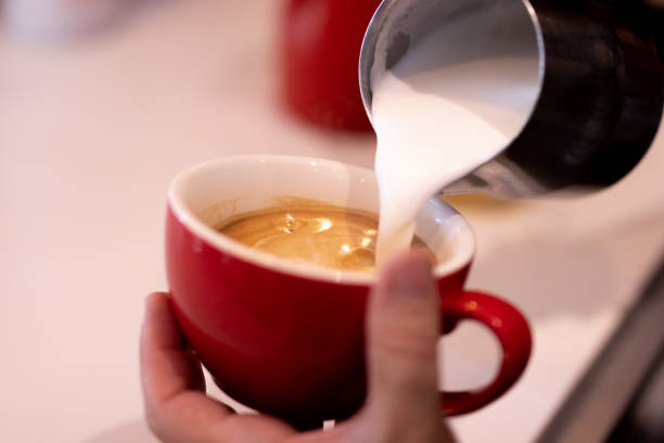 istock Caucasian bartender prepares coffee while pouring milk into red cup 1481008649