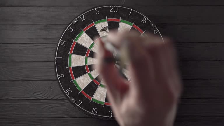 Three darts are aimed and thrown by hand and hit the dartboard on a black wooden background. Unlucky - none of the darts hit the bull's eye. The concept of loss and failure.