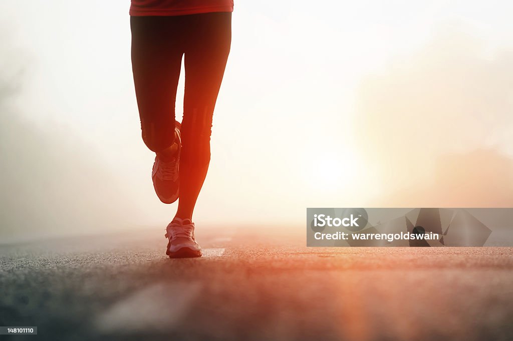 Runner feet sunrise Runner feet running on road closeup on shoe. woman fitness sunrise jog workout wellness concept. Running Stock Photo