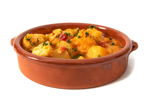Potato stew with cod, served in a clay bowl. Isolated on white background. Spanish food concept.
