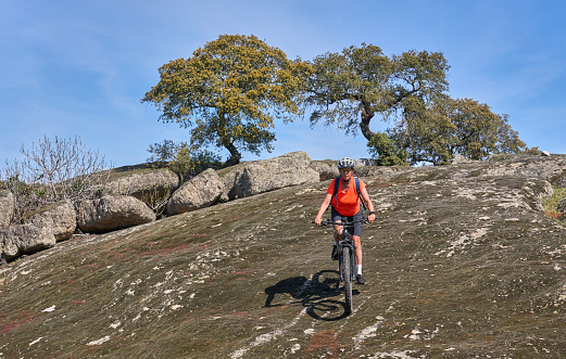 nice senior woman cyling with her electric mountain bike in a stone oak forest of the Extremadura department of Spain