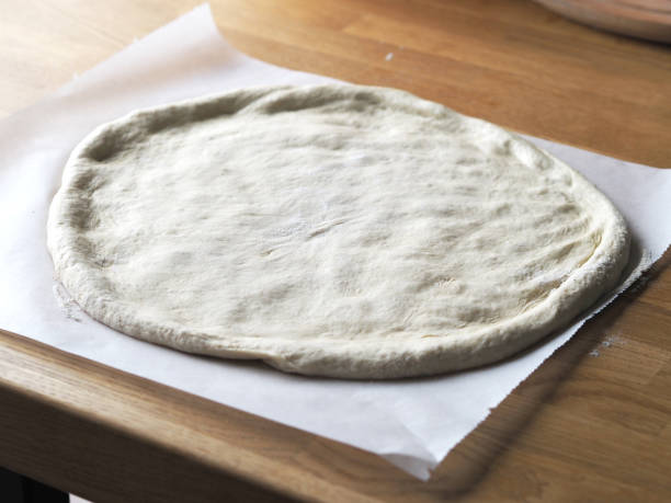 raw pizza dough on a wooden board stock photo