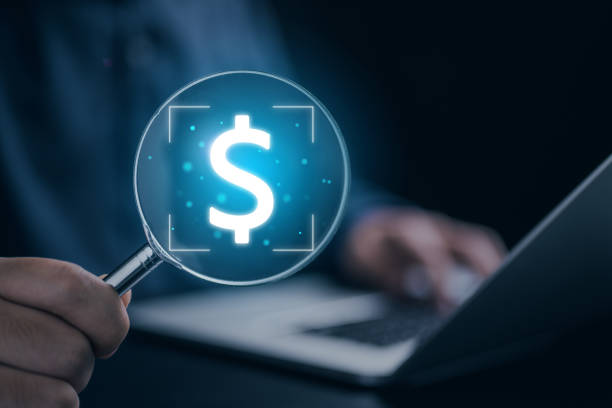 istock Businessman using laptop and holding magnifier with dollar sign 1481021177