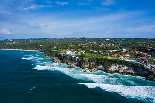 Aerial landscape of Uluwatu coastline in South Bali in Indonesia with powerful waves breaking along the cliffs.