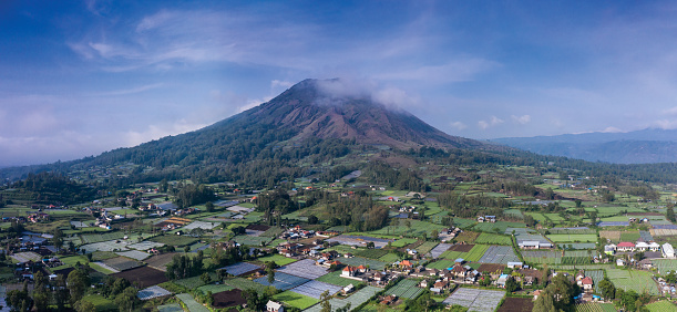 Panoramic landscape of Batur volcano sitting in a volcanic caldeira with local farms in North Bali in Indonesia.