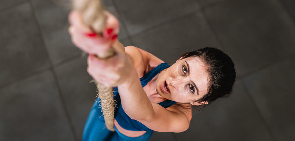 Latin woman training with battle rope in gym