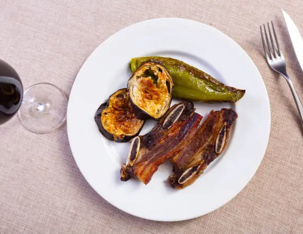 Photo of on white plate-grilled beef ribs with fried eggplant slices and green  pepper.Spanish dish-churrasco