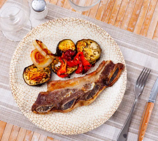 Photo of on blue plate-grilled beef ribs with fried vegetables-aubergine, pepper,onion