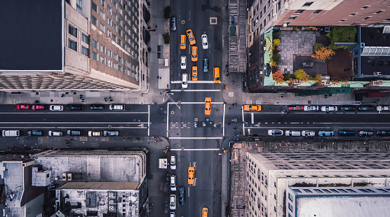 Aerial view of Midtown Manhattan at sunset with a view yellow cabs driving around the city. New York city taxi cabs at the crossroad.