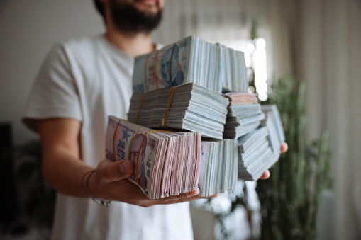 Turkish currency mortgage loan. Hand counting Turkish lira banknotes with building construction background