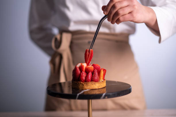 köchin backt einen kuchen mit erdbeeren - konditor stock-fotos und bilder