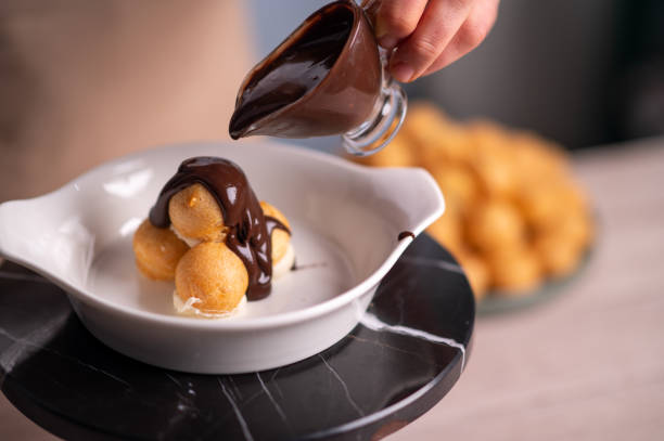 istock Female chef pouring chocolate sauce on profiteroles 1481028929