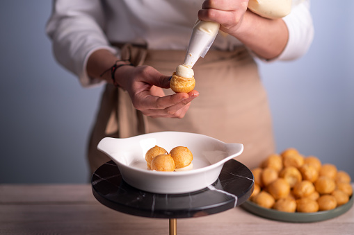 Female chef making profiteroles.