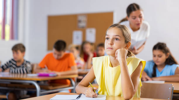 istock Assiduous focused tween girl sitting with pen and notebook at lesson 1481031796
