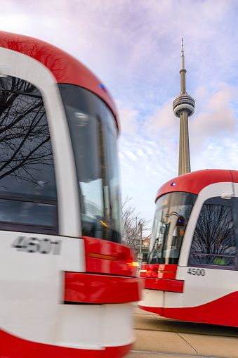 Toronto, Canada - January 26, 2023 : Two street cars passing in front of each other with the CN Tower in the background