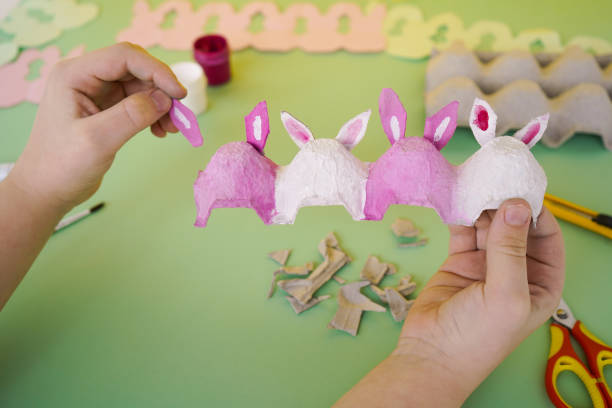 istock Step by step instruction white bunnies made of cardboard packaging from eggs. Zero waste concept. Easter crafts. Step 4 - insert the ears into the slots 1481036448