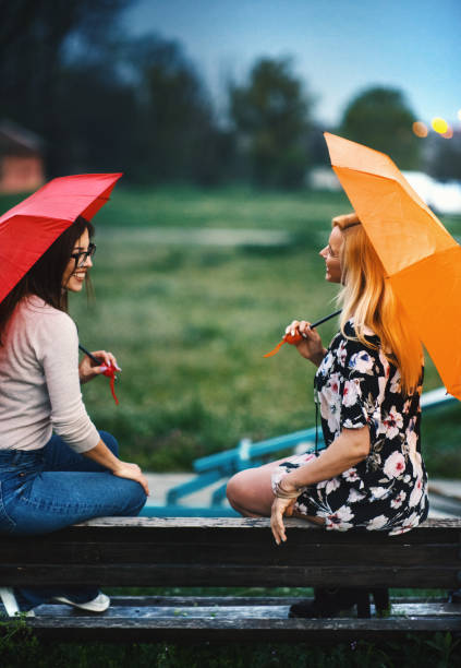 istock Two women with red and orange umbrellas on a nice spring afternoon. 1481037755