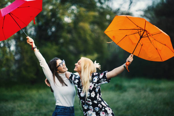 istock Two women with red and orange umbrellas on a nice spring afternoon. 1481037770
