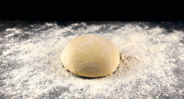 istock Pizza dough on a dark table sprinkled with flour. Baking concept. Italian cuisine. 1481042374