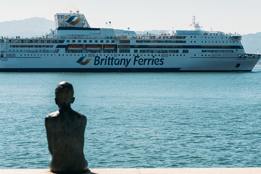 Santander, Spain - April 6, 2023: Defocused view of Statue of the Raqueros in spanish port santander with Brittany Feries in the background