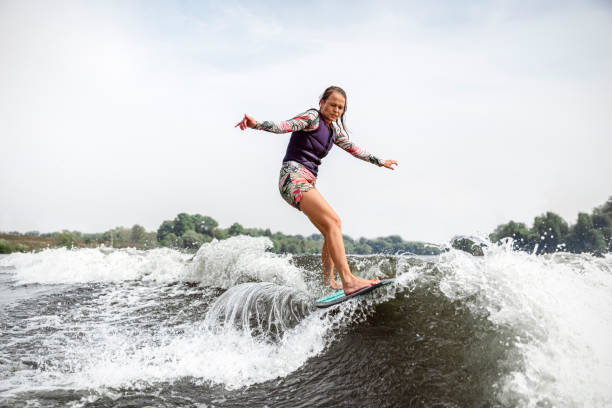 istock Young woman wakesurfing down the river waves 1481044070