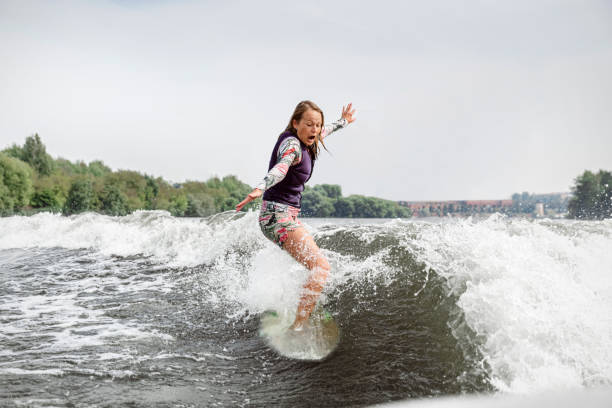 mujer joven despertando por las olas del río - wakeboarding motorboating extreme sports waterskiing fotografías e imágenes de stock
