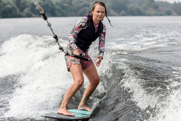 mujer joven despertando por las olas del río - wakeboarding motorboating extreme sports waterskiing fotografías e imágenes de stock