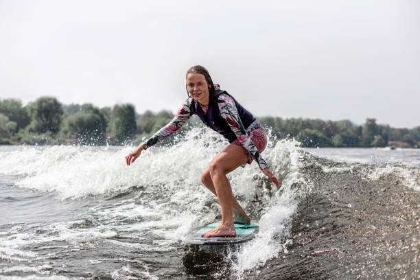 mujer joven despertando por las olas del río - wakeboarding motorboating extreme sports waterskiing fotografías e imágenes de stock