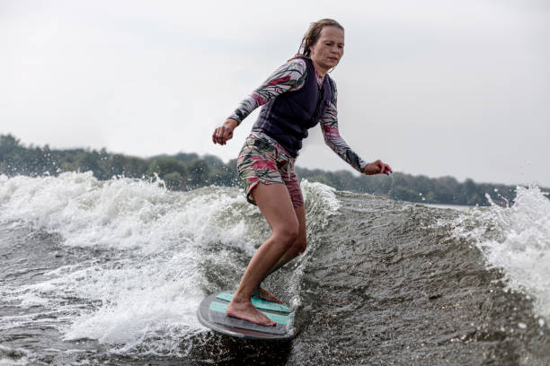 młoda kobieta wakesurfing w dół fal rzeki - wakeboarding motorboating extreme sports waterskiing zdjęcia i obrazy z banku zdjęć